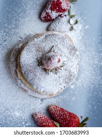 Stack of delicious fluffy pancakes with fresh strawberries and sugar and honey
