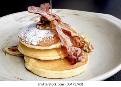 Stack of delicious pancakes with bacon, honey, nuts and caramelize banana