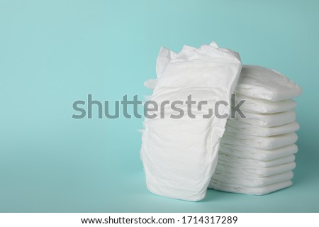 Stack of diapers on light blue background. Space for text