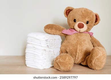 Stack of diapers with toy teddy bear on table.Newborn nappies concept