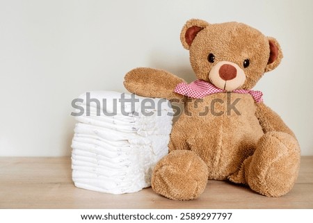 Stack of diapers with toy teddy bear on table.Newborn nappies concept