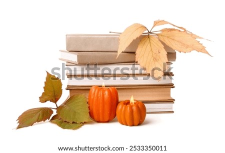Stack of different books, burning candles and autumn leaves on white background