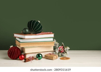 Stack of different books, gift box and Christmas balls on white wooden table