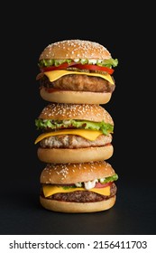 stack of different burgers on black background - Shutterstock ID 2156411703