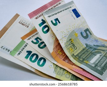 A stack of different euro bills paper banknotes, flat lay close up on a white background. The concept of saving, investment, finance, banking and economy.