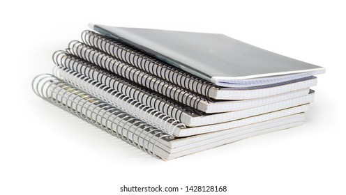 Stack of the different exercise books with wire spiral binding at selective focus on a white background