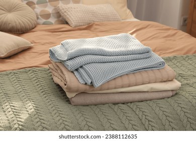 Stack of different folded blankets on bed indoors. Home textile
