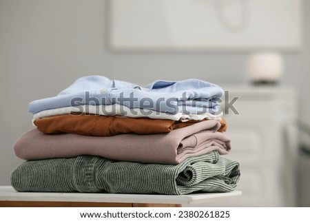 Stack of different folded clothes on bedside table indoors, closeup