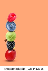 Stack of different fresh tasty berries on light coral background, space for text
