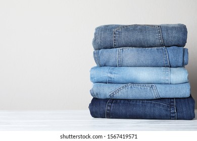 Stack of different jeans on white wooden table. Space for text - Powered by Shutterstock