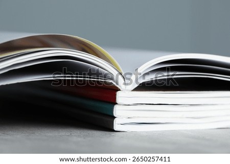 Stack of different magazines on grey table, closeup