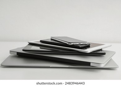 Stack of different modern gadgets on light background