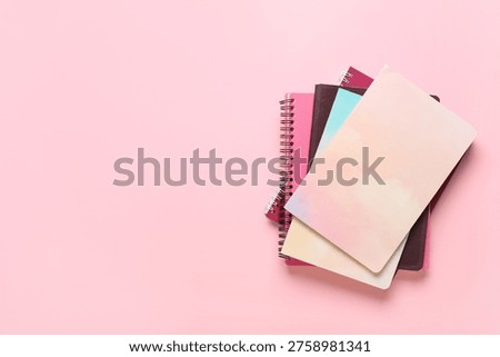 Stack of different notebooks on pink background