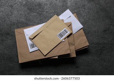 Stack of different paper envelopes on dark grey table, top view. Post office