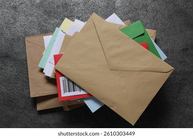 Stack of different paper envelopes on dark grey table, top view. Post office
