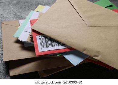 Stack of different paper envelopes on dark grey table, closeup. Post office