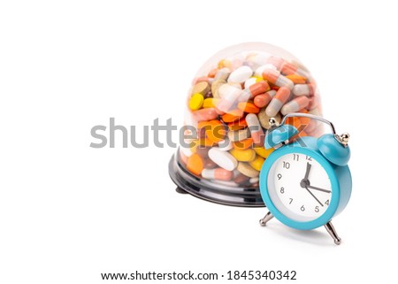 stack of different pills and tablets near clock over white background. copy space. medical dosage schedule concept.