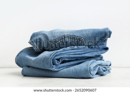 Stack of different stylish jeans pants on white background