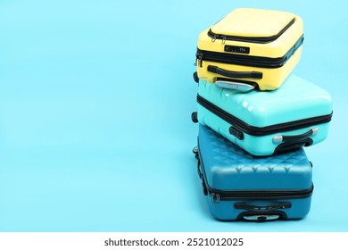 Stack of different suitcases on light blue background, space for text