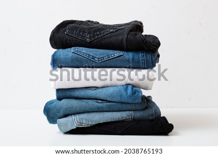 A stack of different types of jeans. Jeans of different colors on a light background.