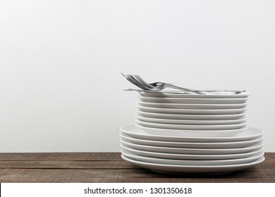 A stack of dishes. tableware on a brown wooden table. plates and cutlery. with space for text