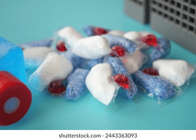 A stack of dishwasher tablets and a bottle of detergent on a blue background