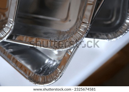 A stack of disposable aluminum foil pans. Heavy duty aluminum. Crimped edges. Storage for leftover food.