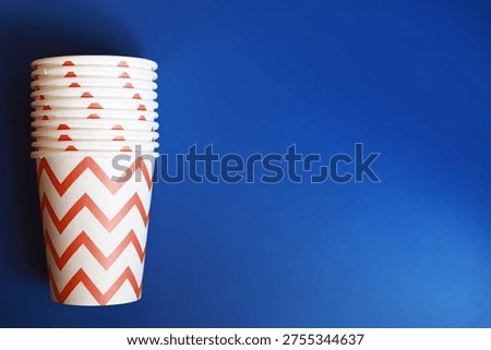 Stack of Disposable Cups with Red Zigzag Pattern on Vibrant Blue Background