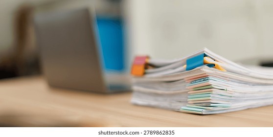 Stack of document files and reports organized with colorful binder clips and sticky notes on a wooden desk, symbolizing office work, business data, and financial administration