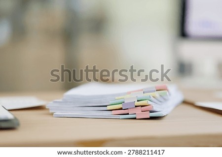 Stack of document papers with colorful file tabs and binder clips on a light wooden table. Representing organization. Administration. Business accounting. And data management in an office environment