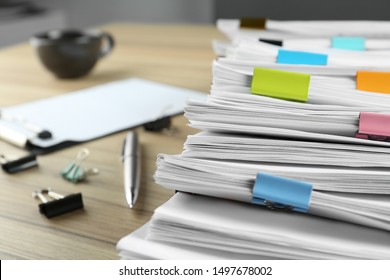 Stack of documents with binder clips and pen on wooden table, closeup view