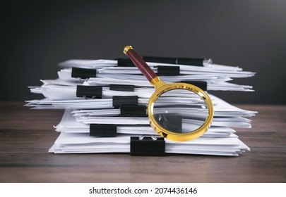 Stack of documents and magnifying glass on the table.