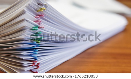 A stack of documents stapled with colorful staples lies on the office desk in the office