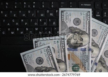 A stack of dollar bills with a keyboard in the background