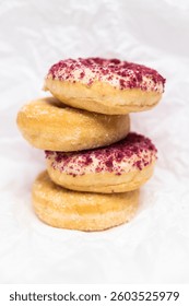 Stack of donuts with berry crumble topping and sugar glaze on a white textured background — sweet, tasty, and inviting dessert concept.Tower of assorted donuts with sugar coat