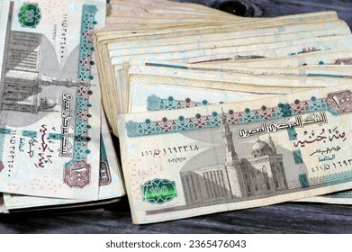 Stack of Egyptian currency of 100 EGP LE one hundred Egyptian pound bills, spending, giving and using money concept, paying and buying using banknotes with Sultan Hassan mosque and the Sphinx - Shutterstock ID 2365476043