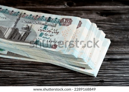 Stack of Egyptian currency of 100 EGP LE one hundred Egyptian pound bills, spending, giving and using money concept, paying and buying using banknotes with Sultan Hassan mosque and the Sphinx