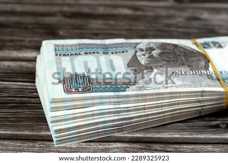 Stack of Egyptian currency of 100 EGP LE one hundred Egyptian pound bills, spending, giving and using money concept, paying and buying using banknotes with Sultan Hassan mosque and the Sphinx