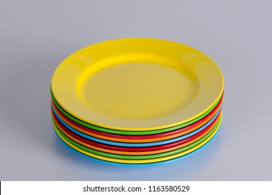 Stack Of Empty Bight Colorful Plates On White Table. Side View. 