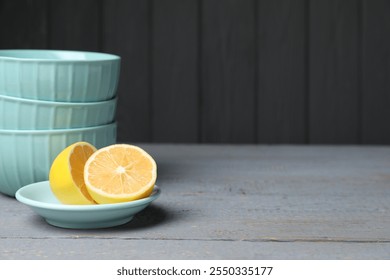 Stack of empty bowls and lemon on grey wooden table. Space for text