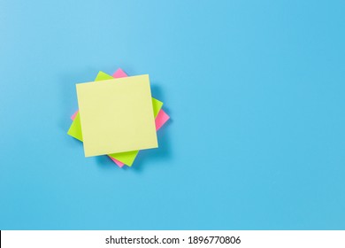 Stack empty sticky post note paper sheet on blue background.