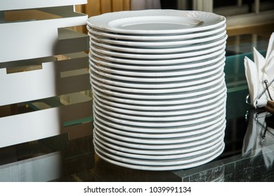 stack of empty white round plates on glass table on catering service banquet