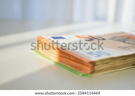 A stack of Euro banknotes, mainly 50 Euro bills, neatly placed on a white table. The image represents financial stability, cash transactions, and wealth management. 