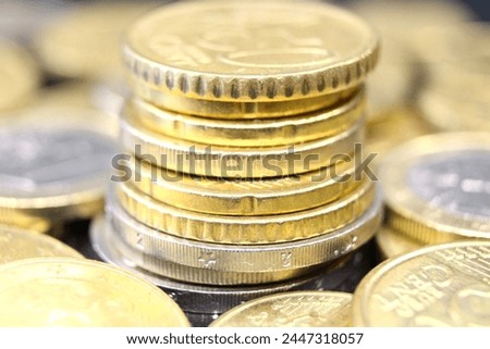 A stack of euro coins in denominations of 20, 50 euro cents and 1, 2 euros, surrounded by euro coins arranged around. Close up view.