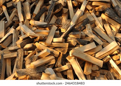 A stack of firewood with a hand chopping block. Chopped firewood for the winter. A lot of firewood - harvesting wood for heating the house. Horizontal photo. Chopped firewood backgrounds and textures