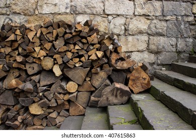 stack of firewood on stairs in front of stone wall