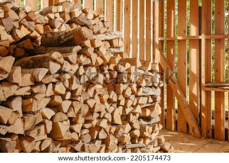 Stack of firewood. Wooden shed for storing firewood indoors. Firewood pile to be used as fuel for heating in fireplaces and furnaces. Wooden wall from pile of firewood stacked in an old farm shed. 