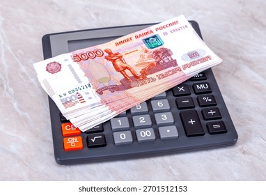Stack of five thousandths banknotes of russian roubles with calculator close up