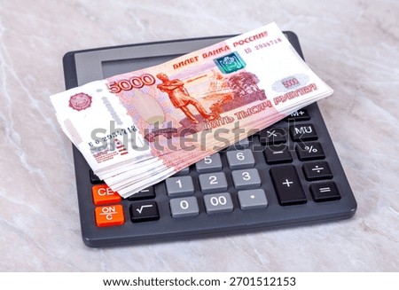 Stack of five thousandths banknotes of russian roubles with calculator close up