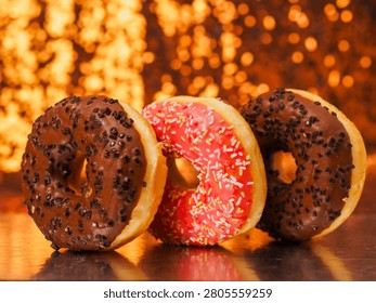 Stack of flattering tasty doughnuts on reflective surface and soft bokeh background. Fine bakery product and delicious dessert. Good for food blogs and industry.